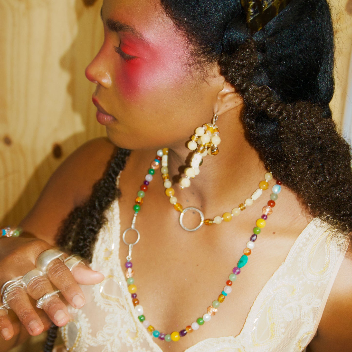 Woman wearing colorful jewelry and a white lace garment against a wooden background